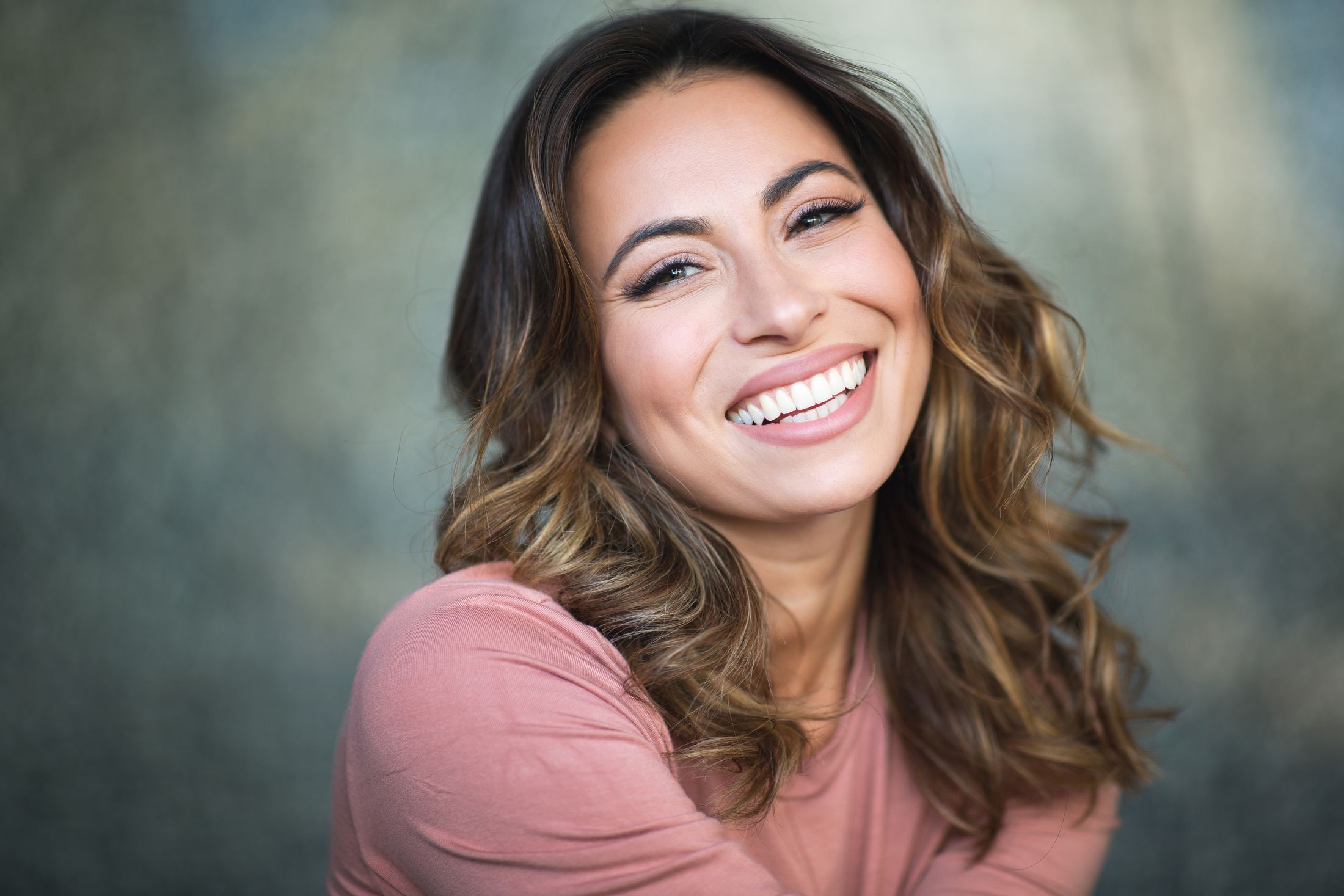 Smiling woman with wavy hair and soft background.