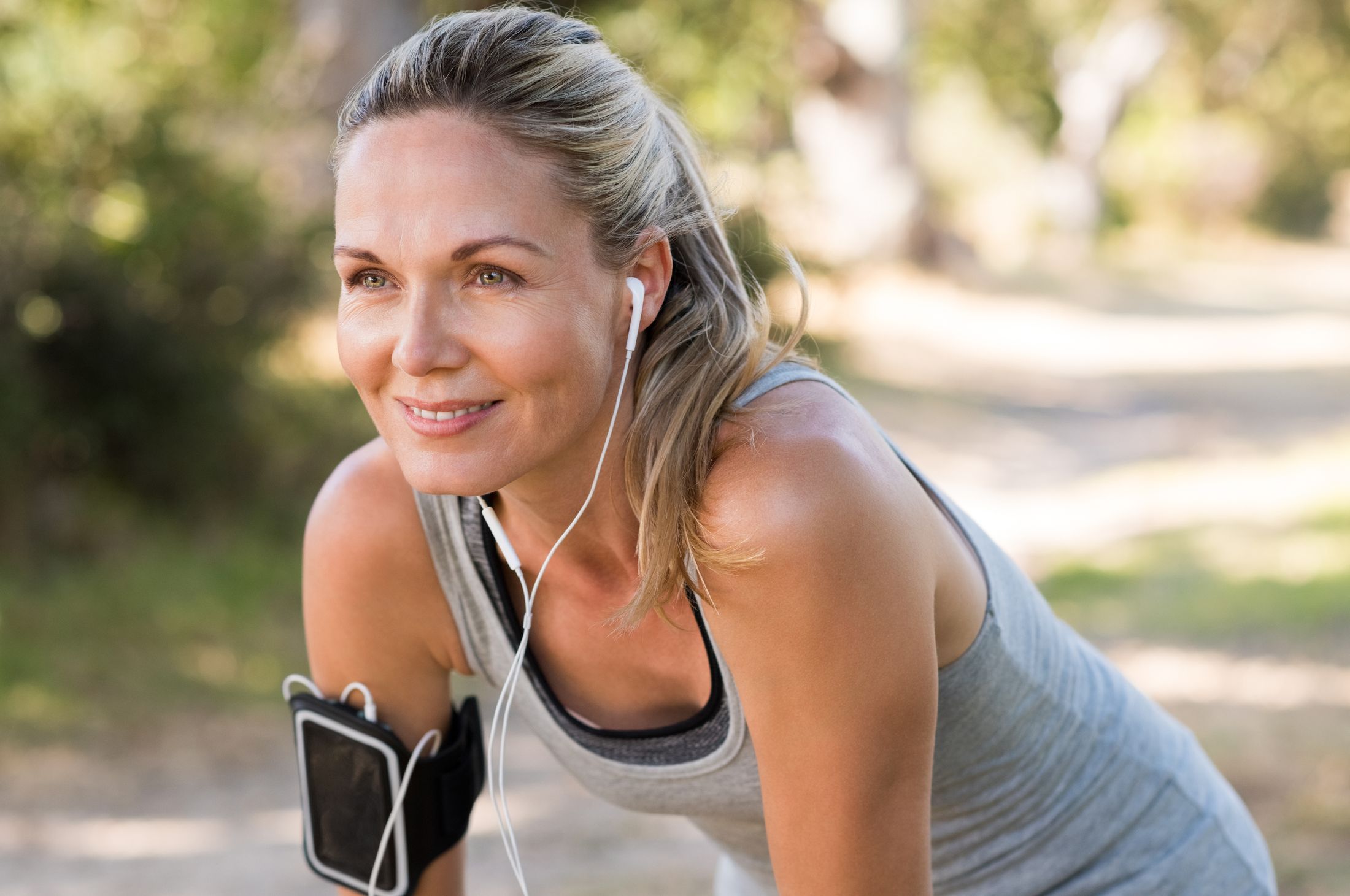 Smiling woman exercising outdoors with headphones.