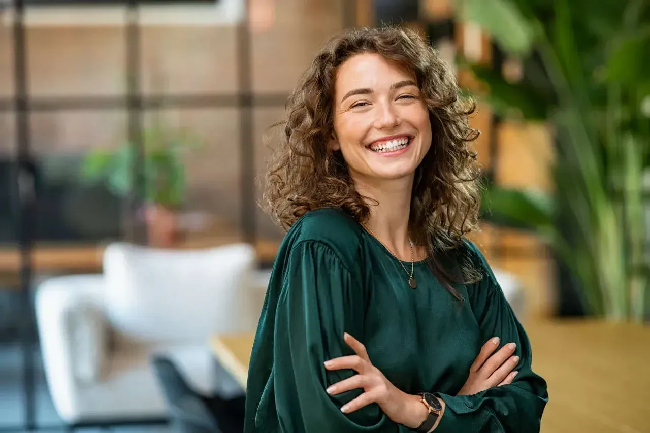 friendly woman indoors smiling and crossing arms