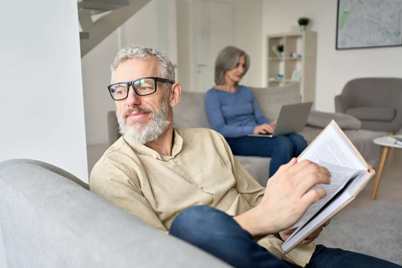 Senior man reading on sofa enjoying increased energy and mental clarity from BHRT