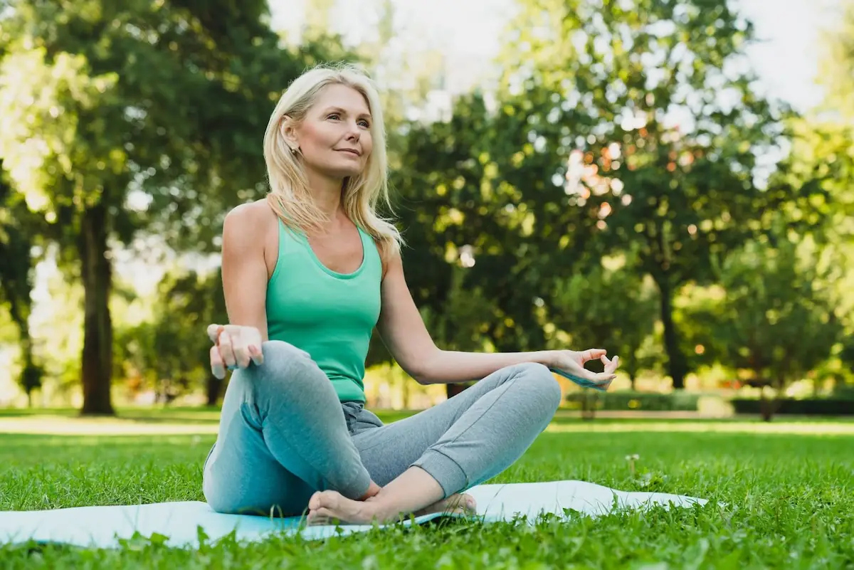 woman in her 50's doing yoga in the park