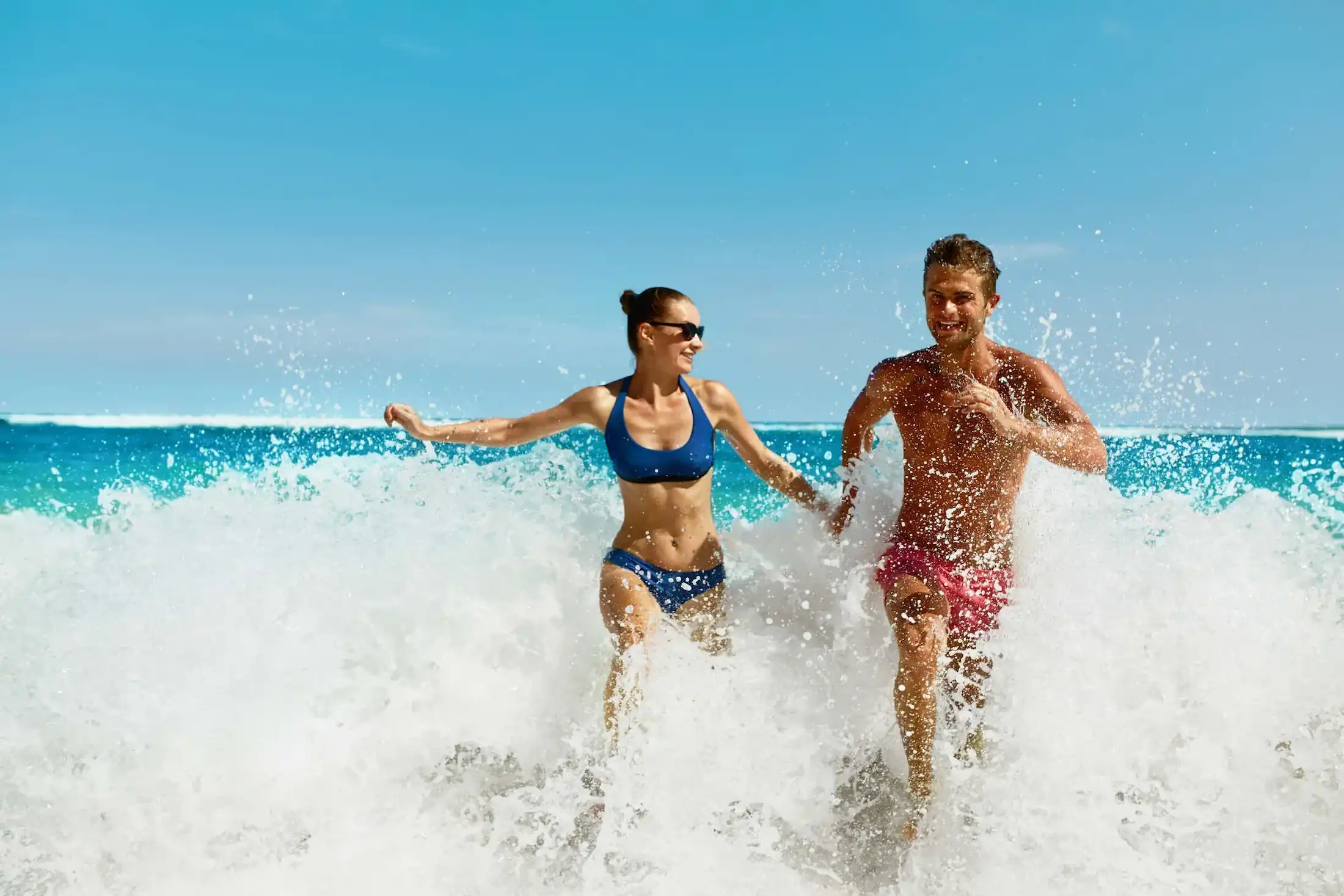 Couple playing in ocean waves on a beach