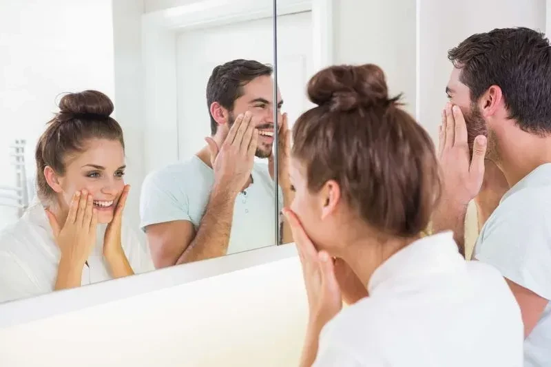 man and women admiring smooth skin in mirror after botox treatment