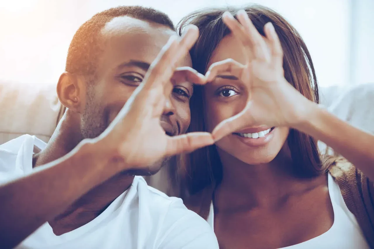 Happy couple making heart with hands