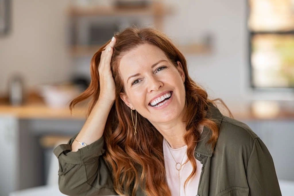 happy woman touching healthy red hair after hair restoration