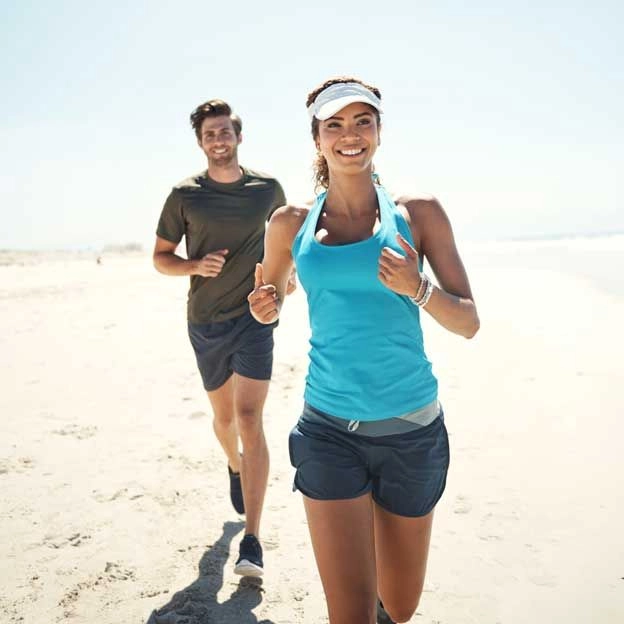 Couple jogging together on the beach during the day